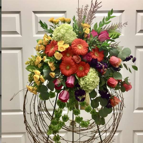 Large mixed floral arrangement on a wire stand with bright roses and gerberas