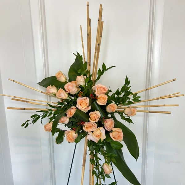 Peach rose arrangement on a bamboo stand with trailing greenery