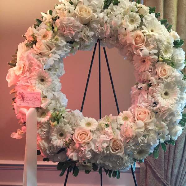 Large pastel floral wreath on a stand with roses and daisies