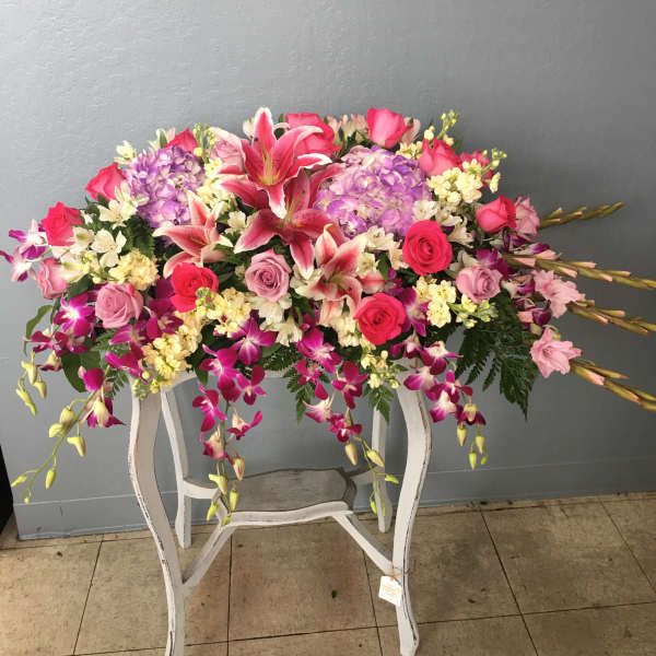 Large pink and purple floral arrangement on a white stand