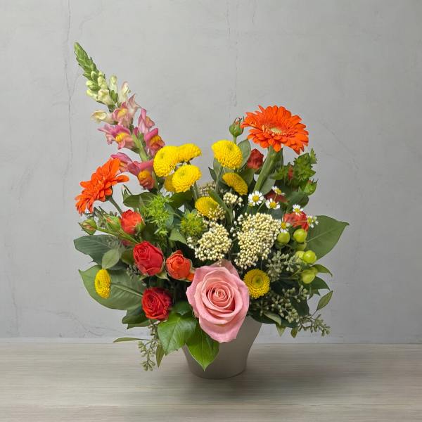 Mixed bouquet in a gray vase with pink and orange blooms