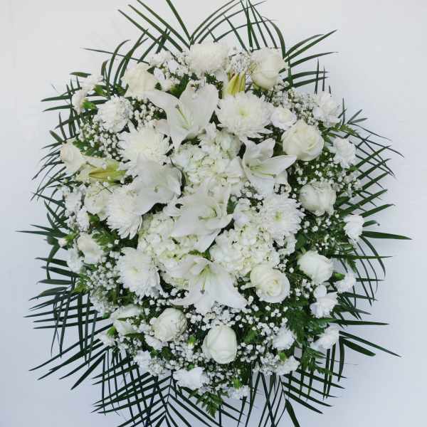 White funeral spray with lilies, roses, and chrysanthemums on a stand