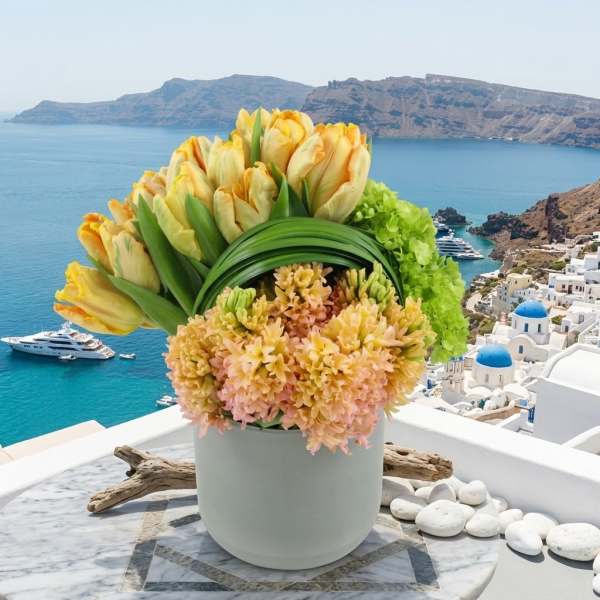 Yellow tulips and peach flowers arranged in a white pot