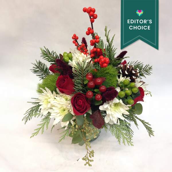 Holiday bouquet with red roses, white daisies, and berries in a vase