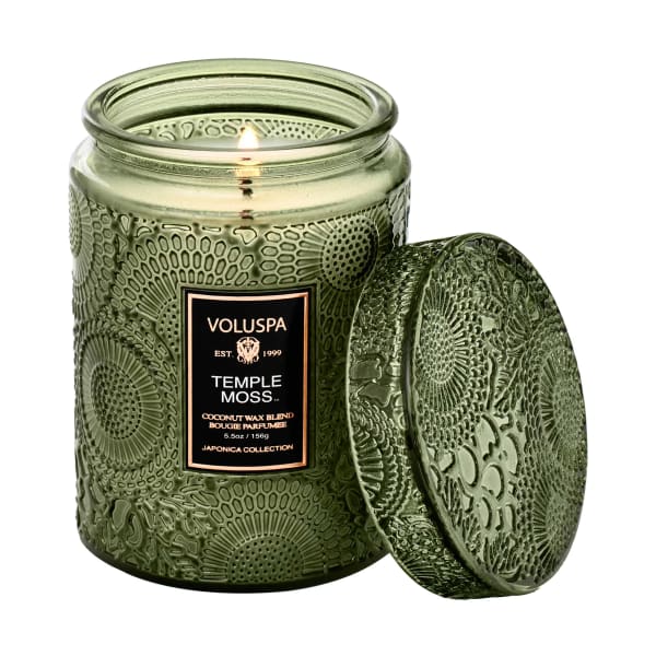 Green glass candle jar with a lit wick and matching lid
