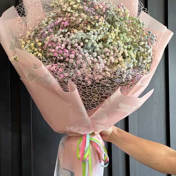 Large pastel bouquet of tiny multicolored flowers wrapped in pink paper
