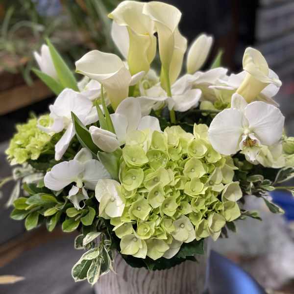 White calla lilies and green hydrangeas in a glass vase