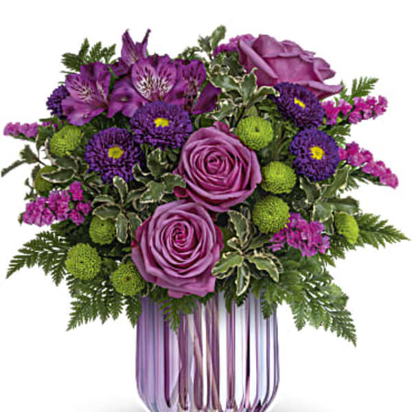 Purple roses and mixed purple flowers in a pink glass vase