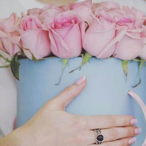 Pink roses arranged in a light blue hatbox with a ribbon handle