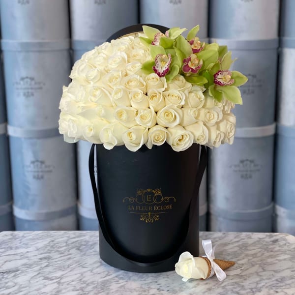 White rose bouquet in a black hat box with green orchids