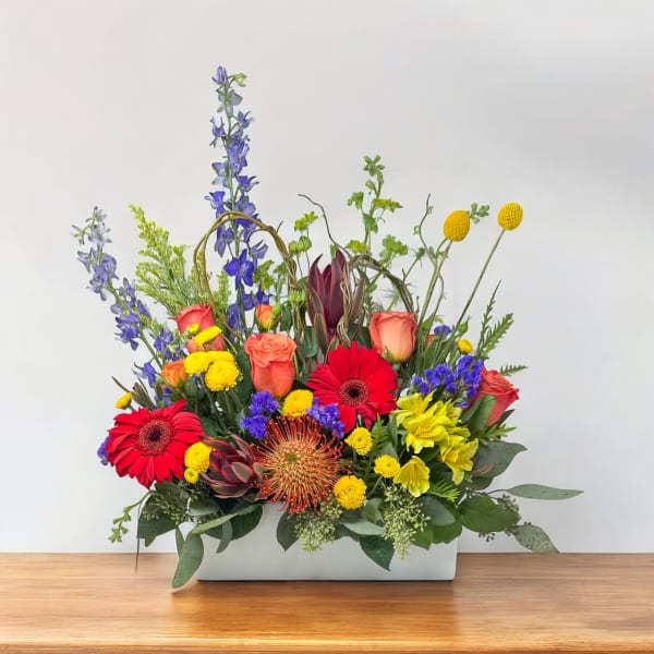 Colorful mixed flower arrangement in a white rectangular vase