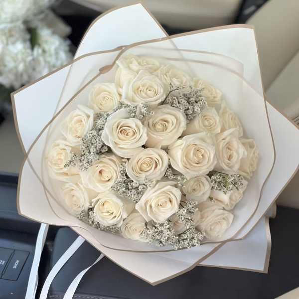 Bouquet of cream roses with small white filler flowers in white wrap
