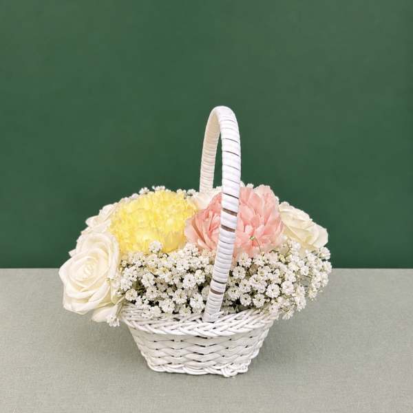 White wicker basket with pastel roses, carnations, and small white filler flowers