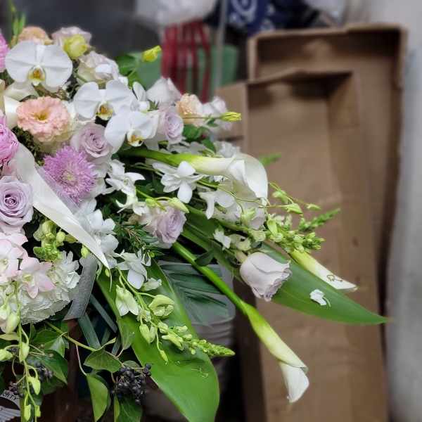 Large pastel floral arrangement with roses, orchids, and white blooms