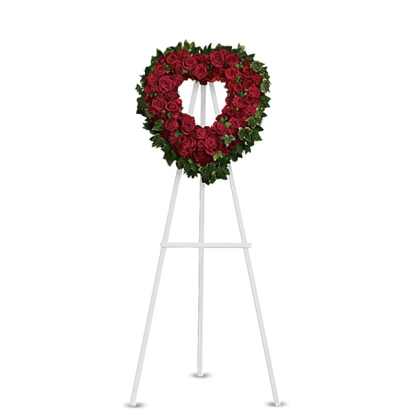 Heart-shaped red rose wreath on a white easel stand