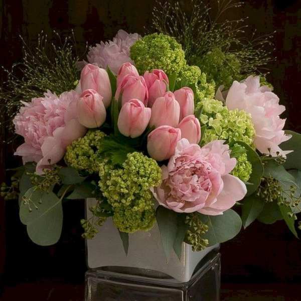 Pink tulips and peonies arranged in a white vase