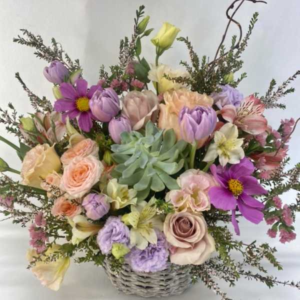 Mixed pastel bouquet in a woven basket with roses and tulips