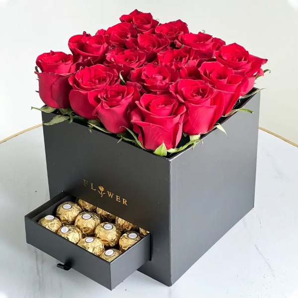 Red roses in a black box with a drawer of gold-wrapped chocolates