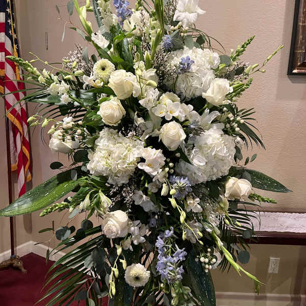 Large white floral standing arrangement with roses and orchids