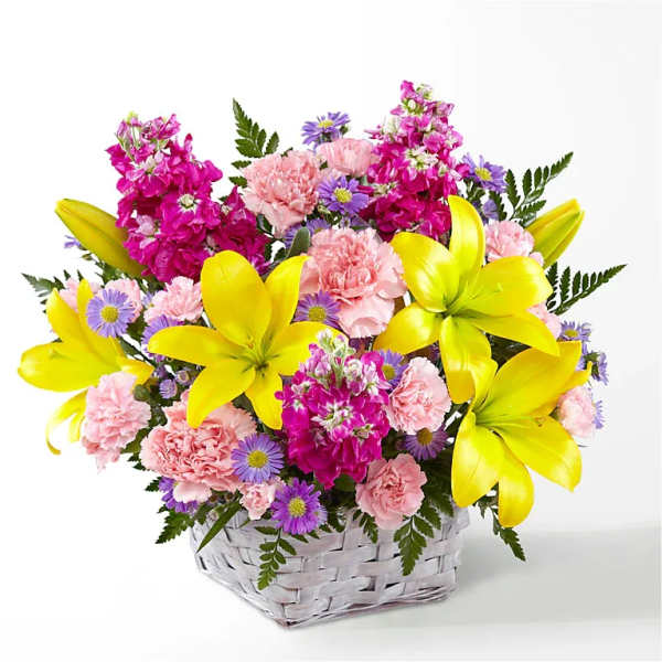 Basket arrangement of yellow lilies, pink carnations, and purple daisies