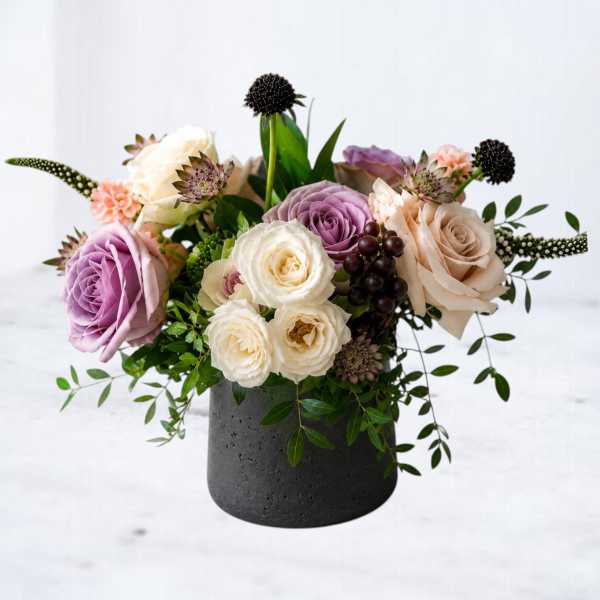 Mixed roses and small accent flowers arranged in a black vase