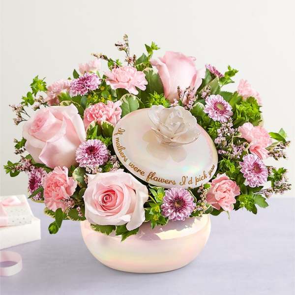 Pink roses, carnations, and mums arranged around a lidded iridescent keepsake bowl