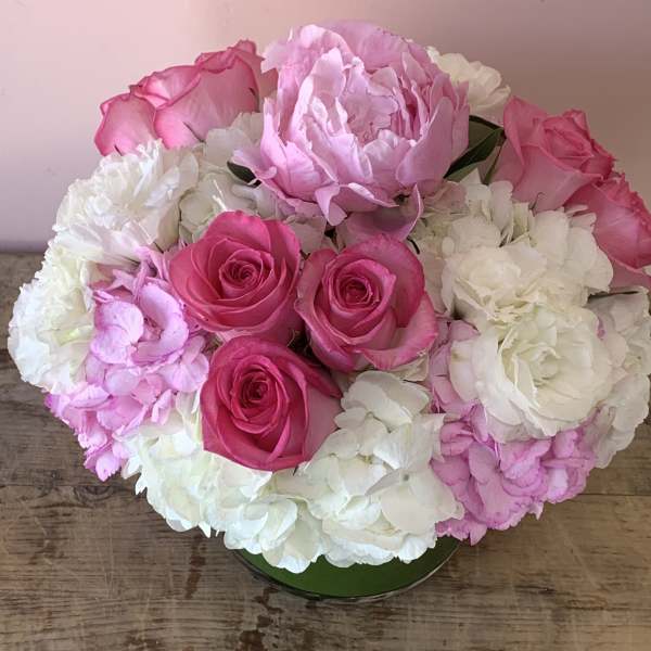 Pink roses and white hydrangeas arranged in a low round container