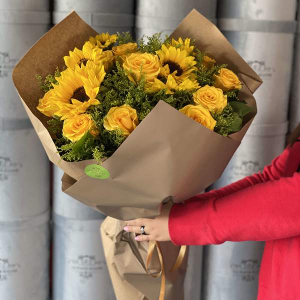 Bouquet of yellow sunflowers and roses wrapped in brown paper