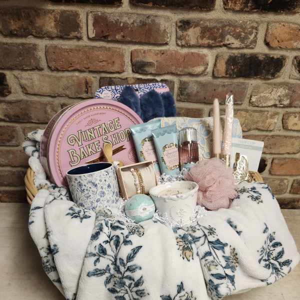 Gift basket with candles, bath items, and accessories on a floral blanket