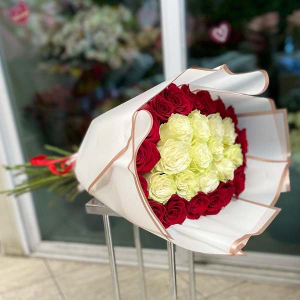 Bouquet of red and pale yellow roses wrapped in white paper