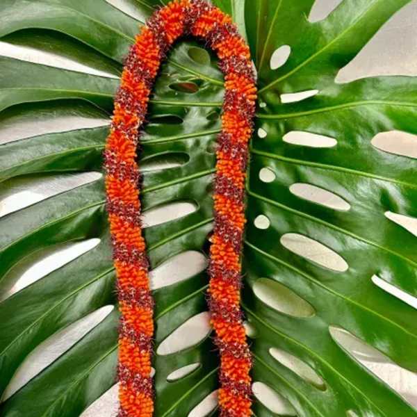 Orange flower lei on large split green leaves