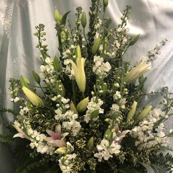 Tall white floral arrangement with lilies and small white blooms in a basket
