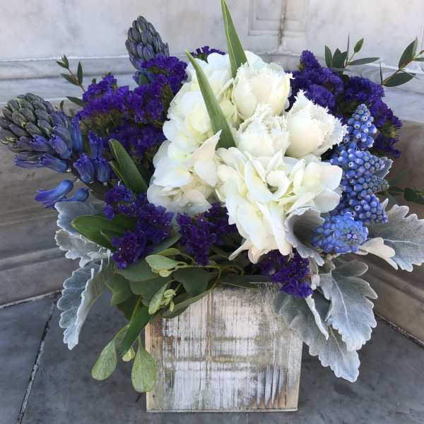 White and purple floral arrangement in a rustic wooden box