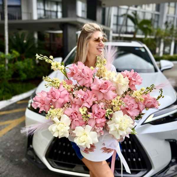 Large pink and white bouquet held in front of a white car