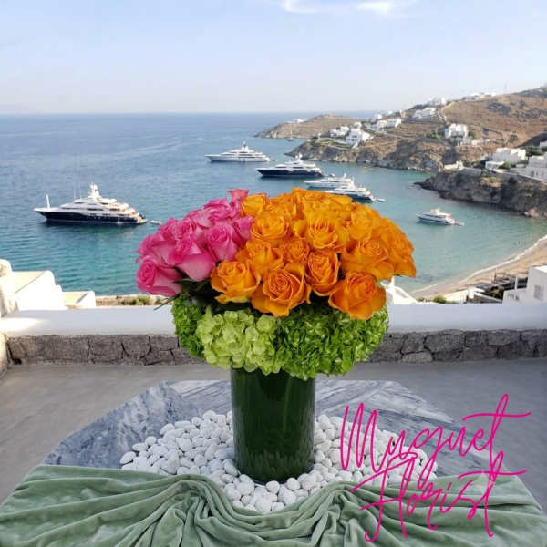 Pink and orange roses arranged in a tall green vase