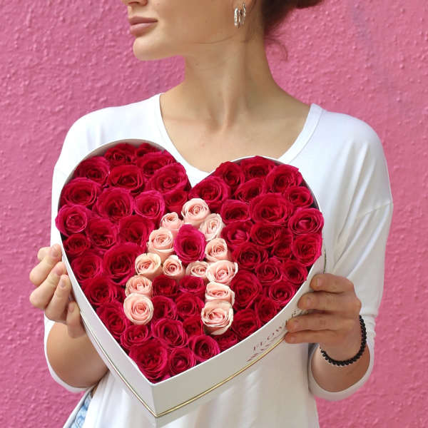 Heart-shaped box of red and pink roses held by a woman