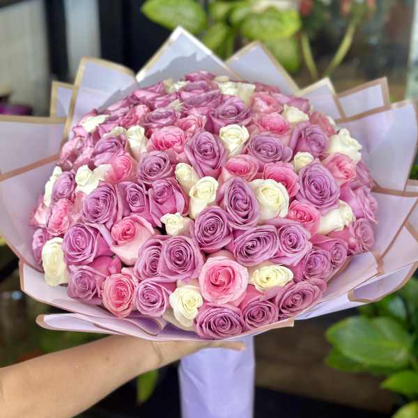 Large bouquet of pink, lavender, and white roses wrapped in pastel paper