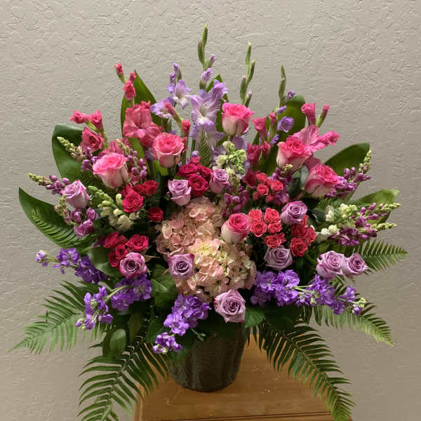 Large pink and purple floral arrangement in a dark vase