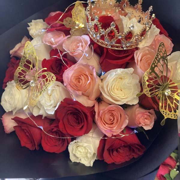 Bouquet of red, pink, and white roses with butterfly toppers and a jeweled crown