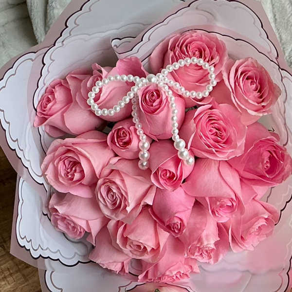 Bouquet of pink roses wrapped in decorative paper with a pearl bow