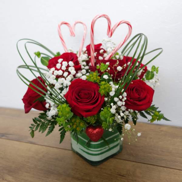 Red roses in a striped glass vase with candy cane hearts