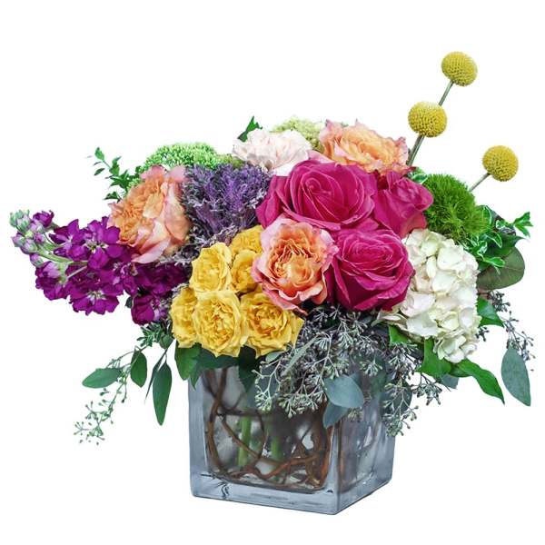 Colorful bouquet of roses and mixed blooms in a square glass vase