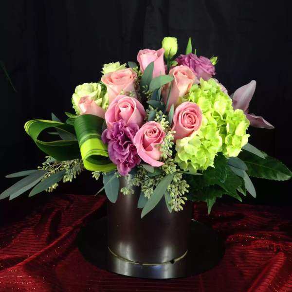 Pink roses and green hydrangeas arranged in a black vase