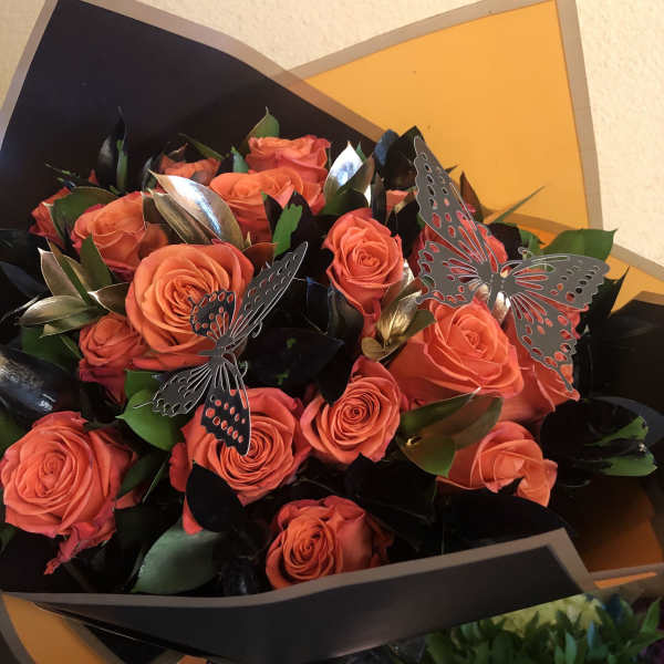 Bouquet of orange roses with butterfly decorations in black and orange wrap