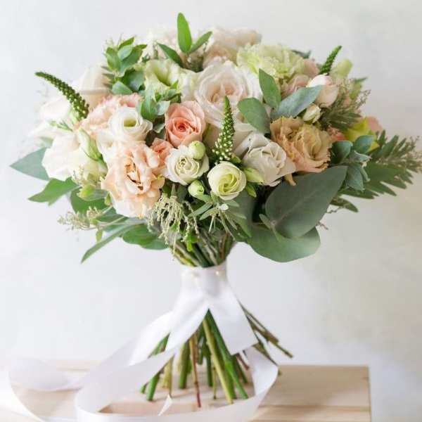 Bouquet of blush and white roses with greenery tied with a white ribbon