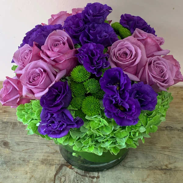 Purple and pink roses with green chrysanthemums in a glass vase
