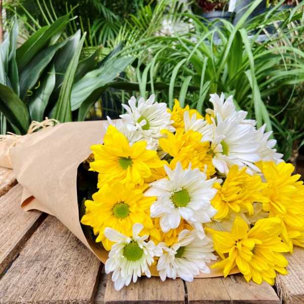 Bouquet of yellow and white daisies wrapped in kraft paper