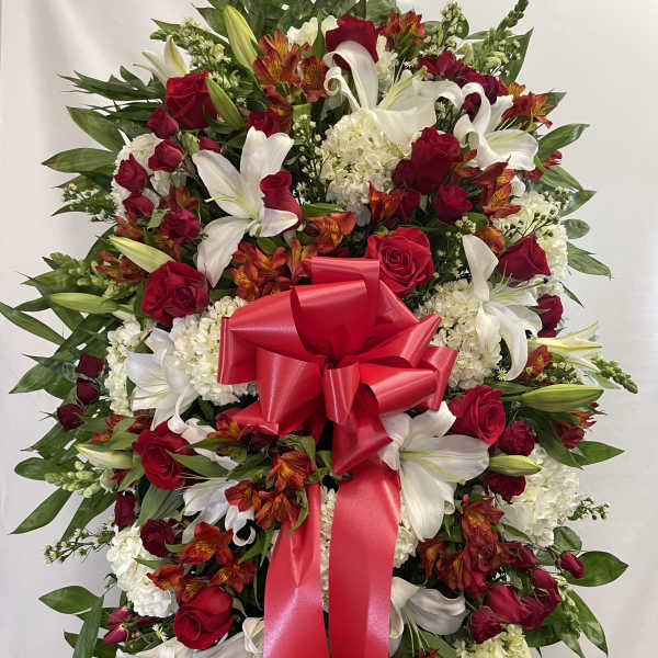 Standing floral spray with red roses, white lilies, and a red ribbon bow