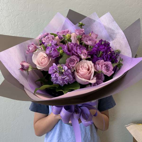 Bouquet of pink and purple roses wrapped in lavender paper