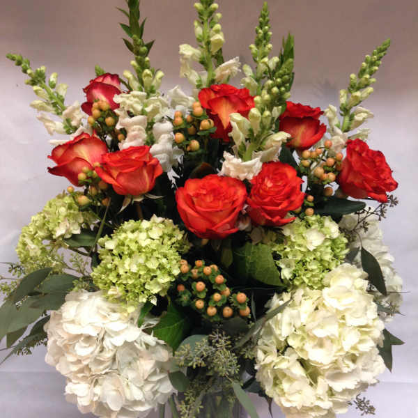 Red roses and white hydrangeas in a clear glass vase
